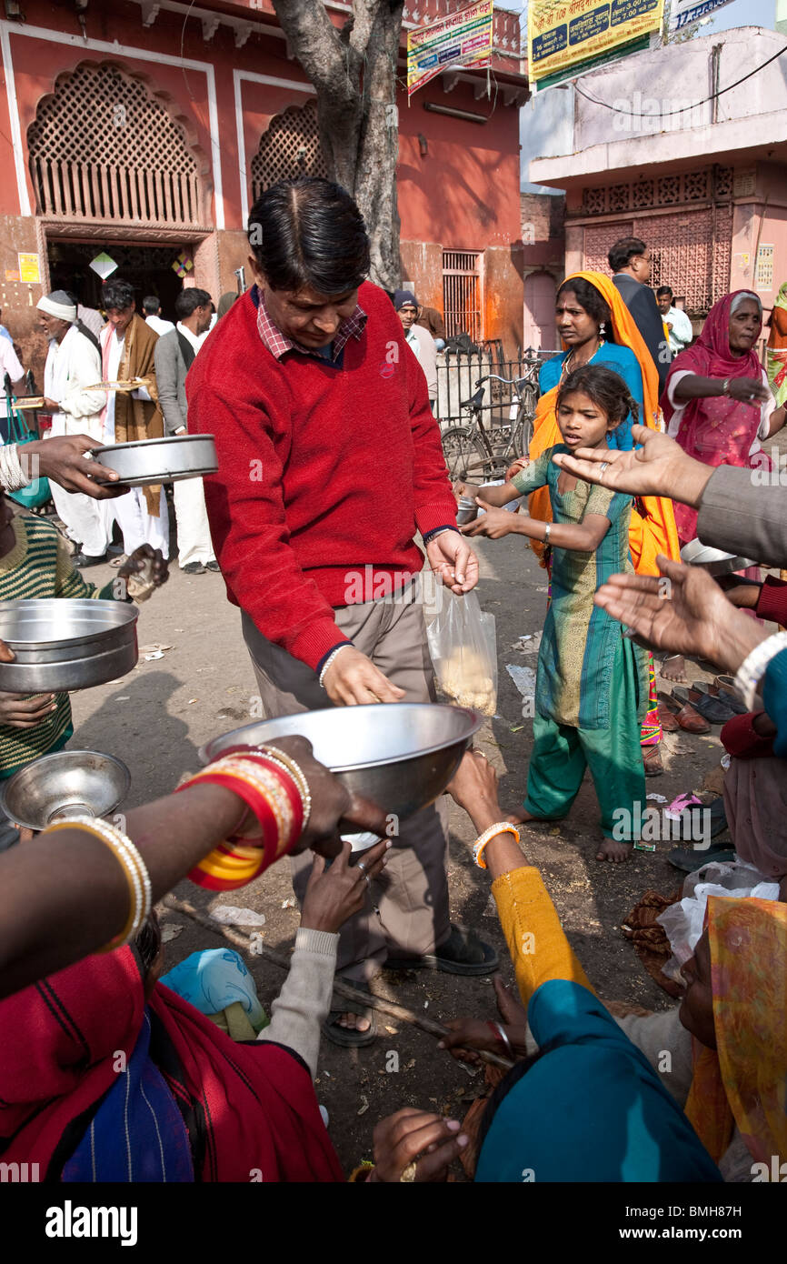 Uomo di dare il cibo ai mendicanti. Jaipur. Il Rajasthan. India Foto Stock