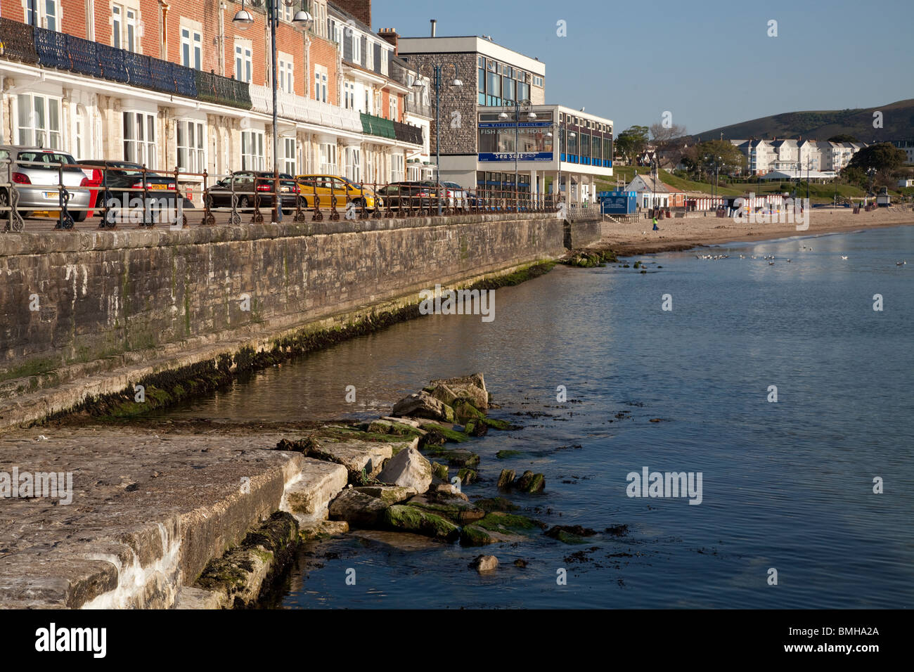 Il lungomare, il mare a parete, scivolo e pennelli di pietra a Swanage in la mattina di sole Foto Stock