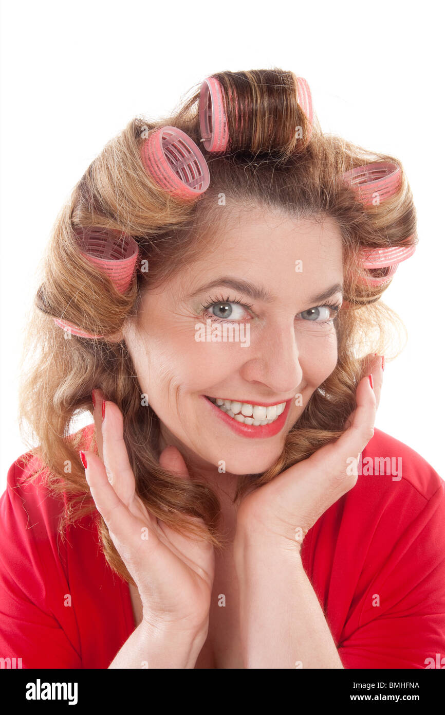 Felice di mezza età della donna in rosso con i capelli rulli - isolato su bianco Foto Stock
