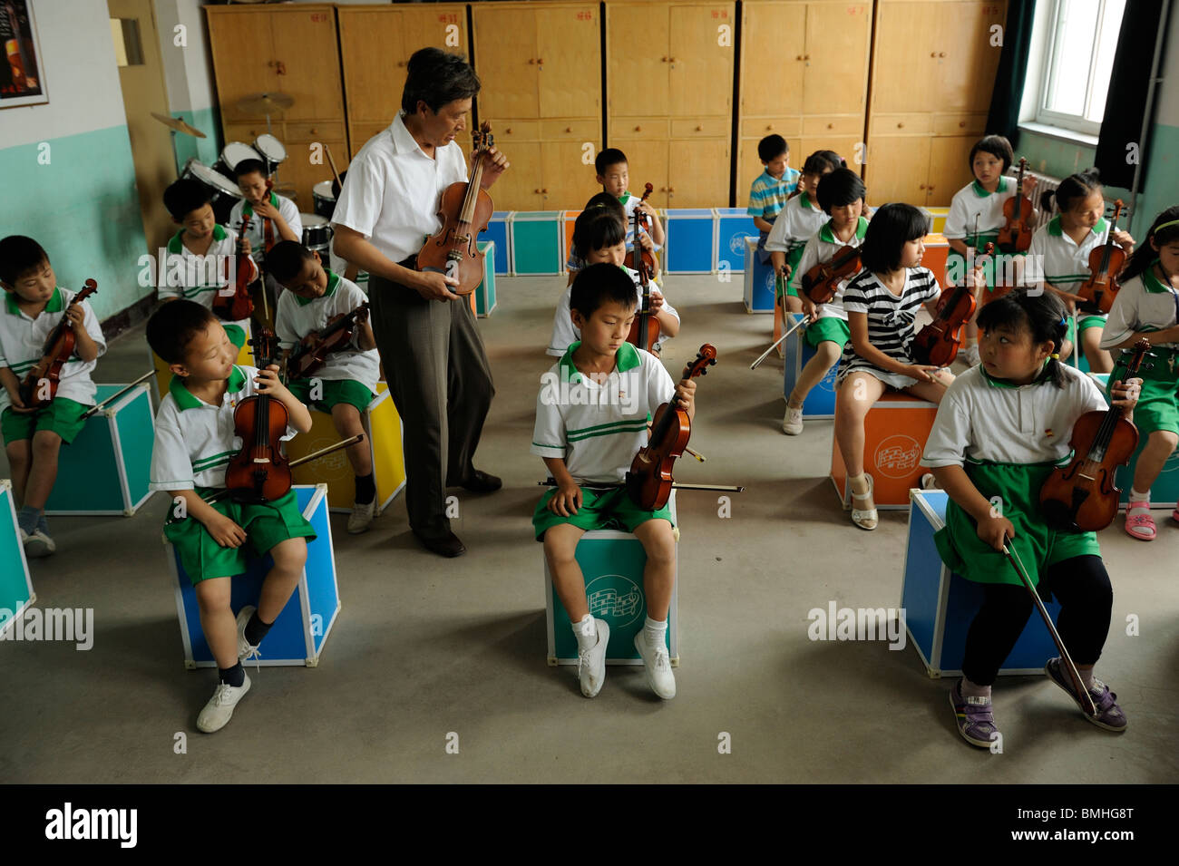 Il sig. Gao Defa insegnando agli studenti di giocare i violini durante una lezione di musica a Dawangwu scuola primaria in Pinggu, Pechino, Cina. 2010 Foto Stock