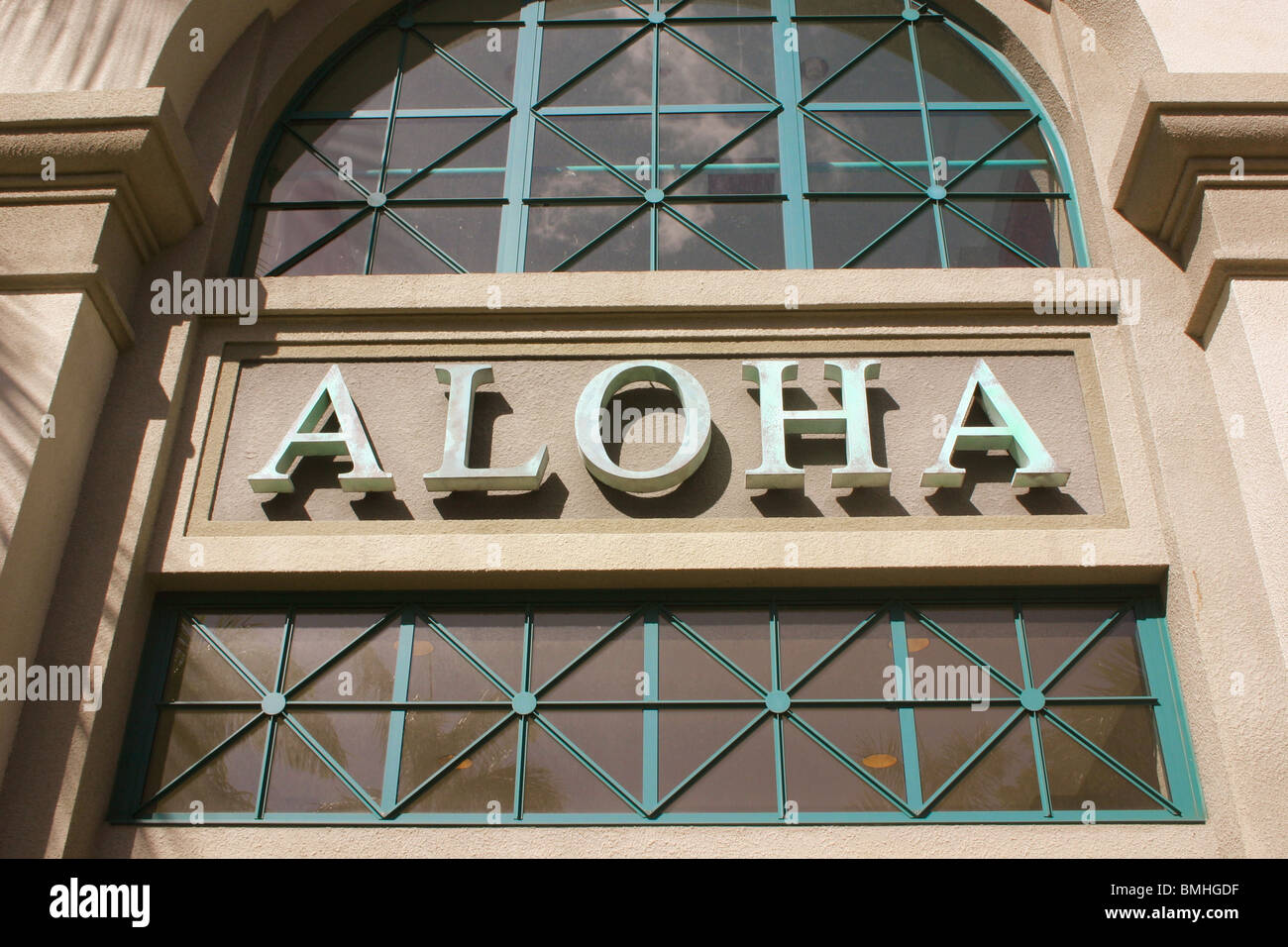 Primo piano della parola Aloha sul lato di Aloha Tower al tramonto con ombra di palm frond Honolulu Oahu, Hi Foto Stock