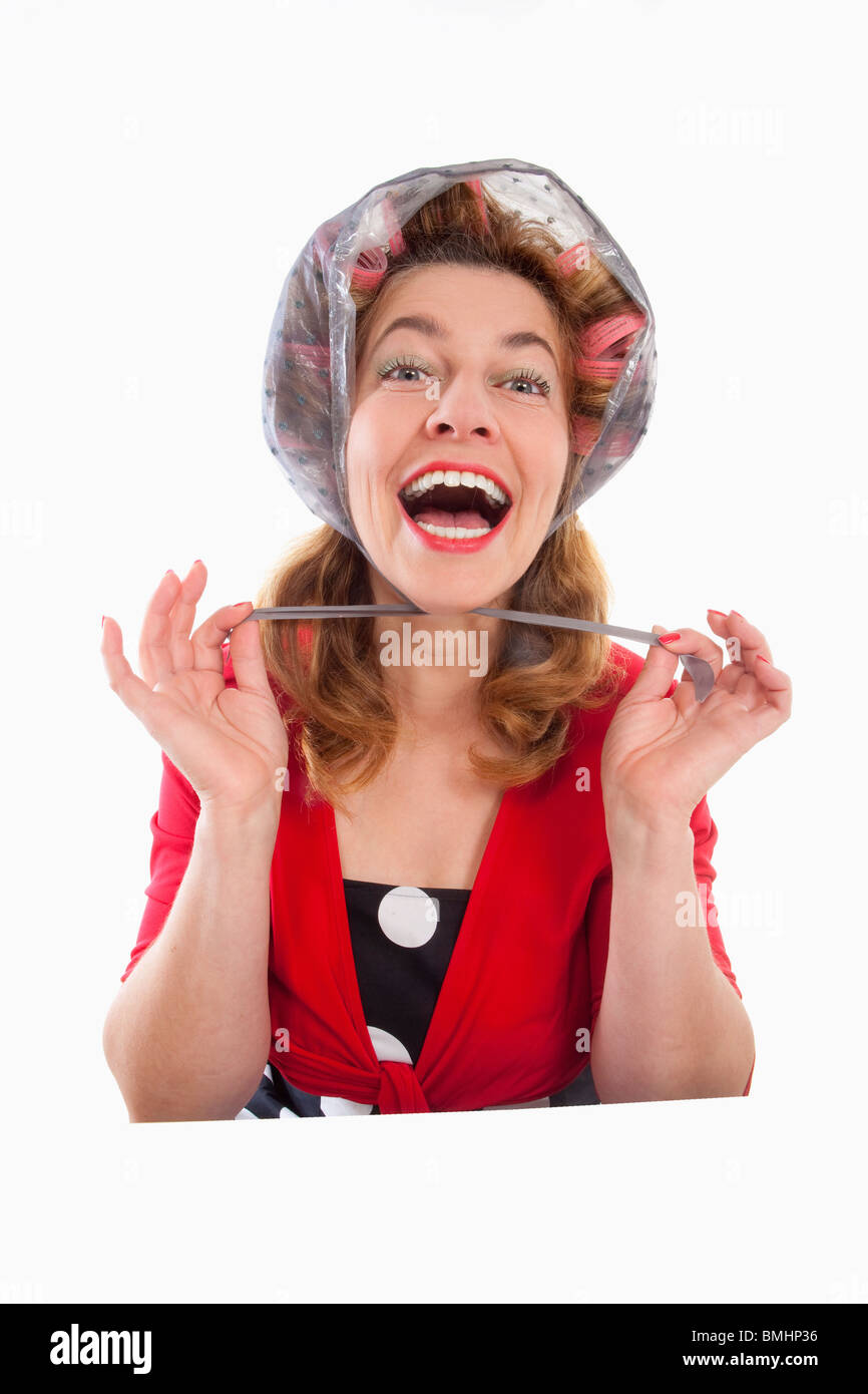 Felice di mezza età della donna in rosso con i capelli rulli - isolato su bianco Foto Stock