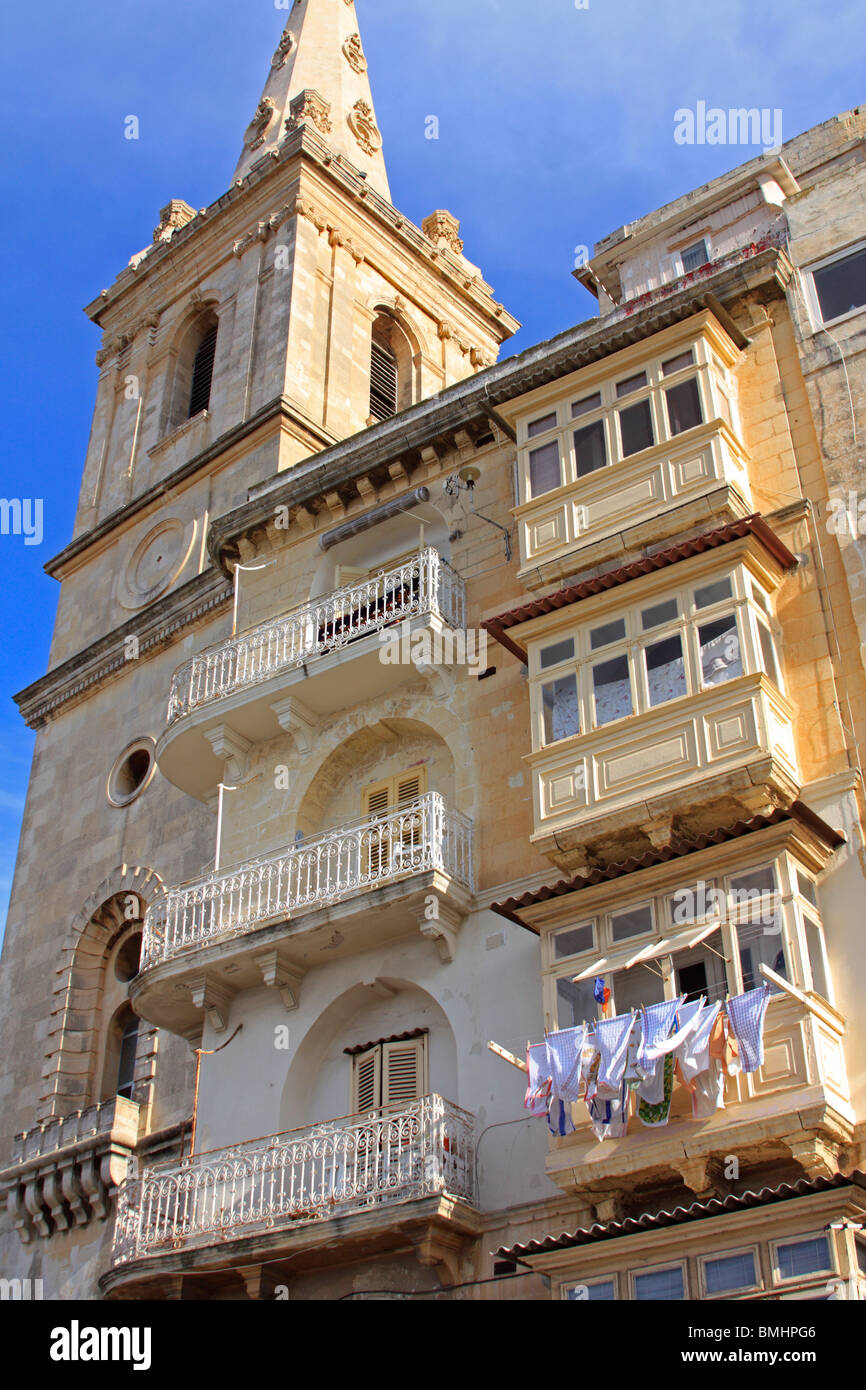 La torre di San Paolo Cattedrale Anglicana di La Valletta, Malta. Adiacente è una tradizionale casa Maltese con balconi chiusi Foto Stock