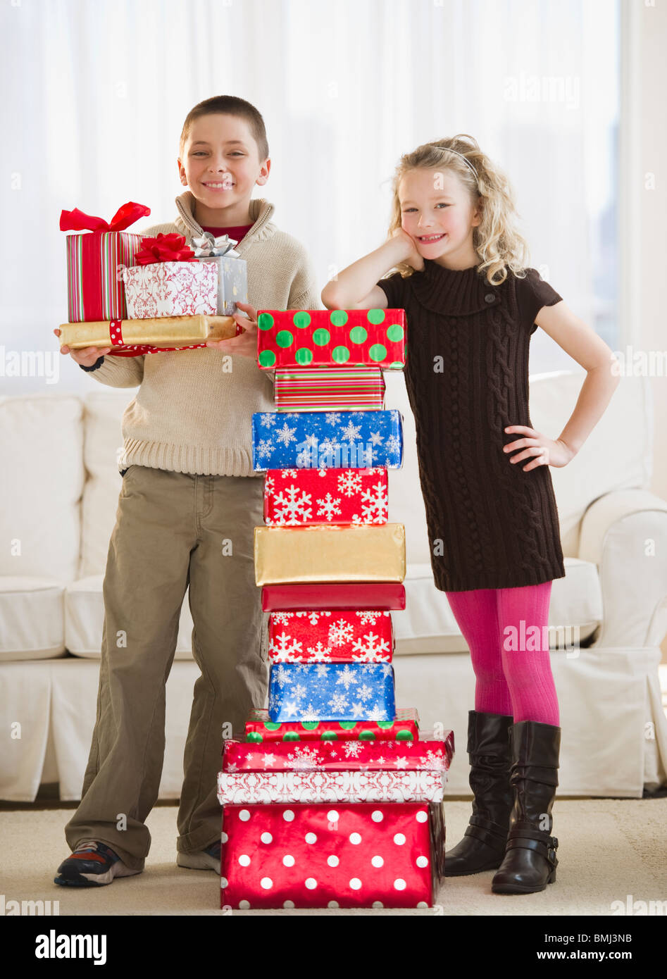 I bambini accanto a una pila di regali di Natale Foto Stock