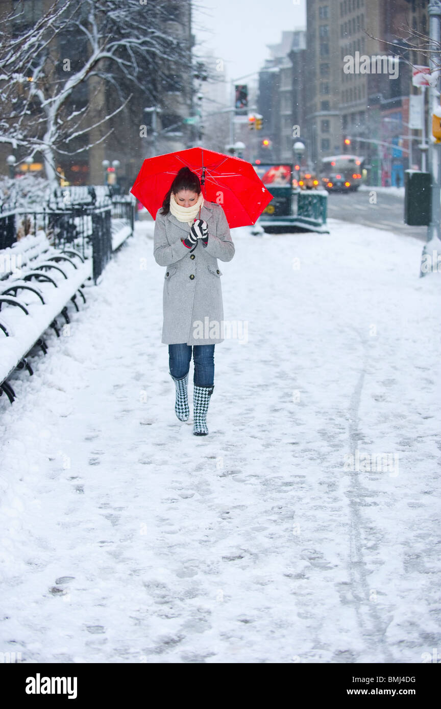 Donna che cammina con ombrellone rosso sulla neve giorno Foto Stock