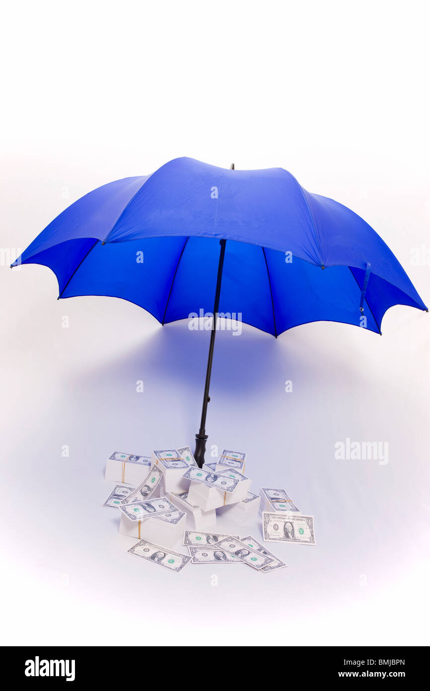 Ombrello che copre le pile di denaro Foto Stock
