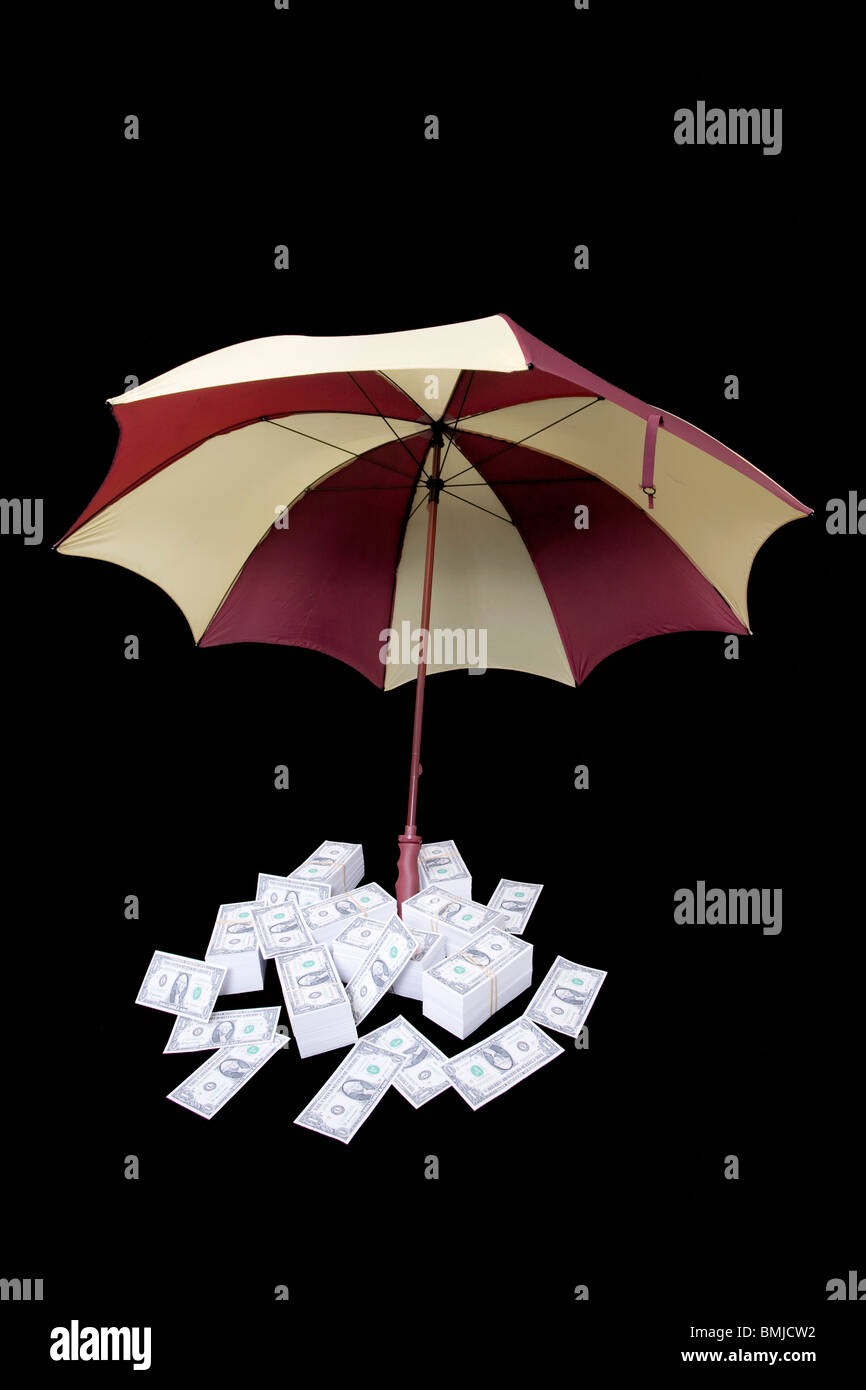 Ombrello che copre le pile di denaro Foto Stock
