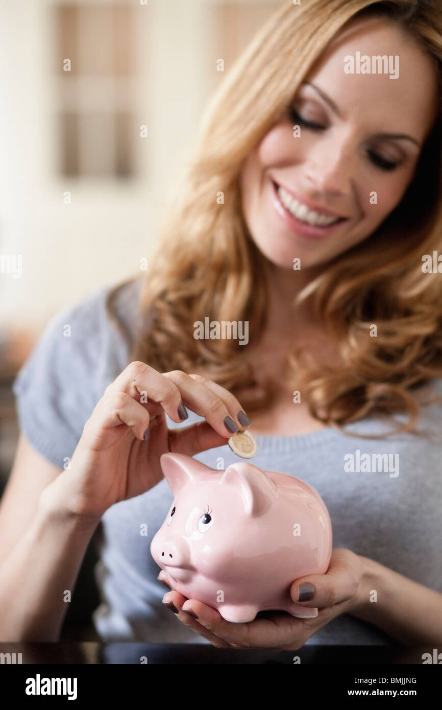 Donna di risparmio di denaro nel salvadanaio Foto Stock