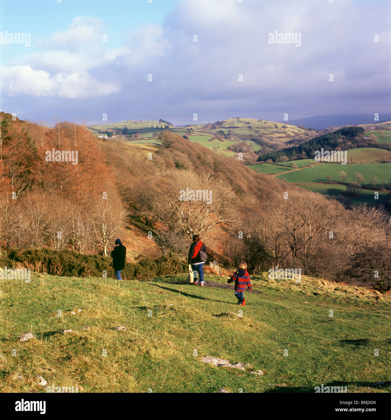 Una giovane famiglia a piedi giù per la collina in inverno da una visita a Carreg Cennan Castello, Trapp, Wales, Regno Unito Foto Stock
