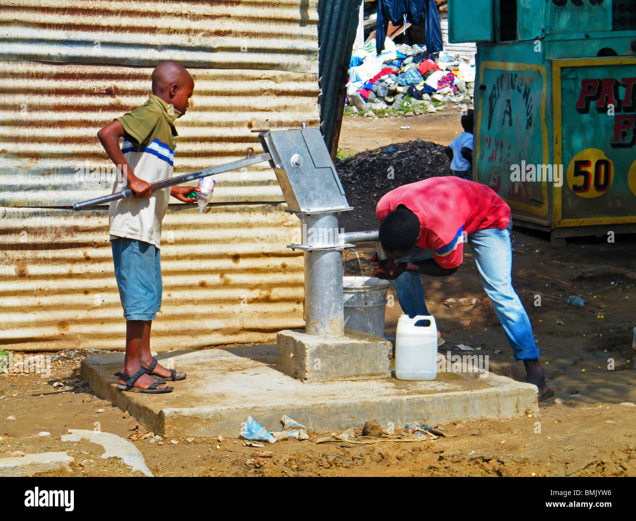 Bambini haitiani bere bere acqua da una pompa n Ouanaminthe, Haiti Foto Stock