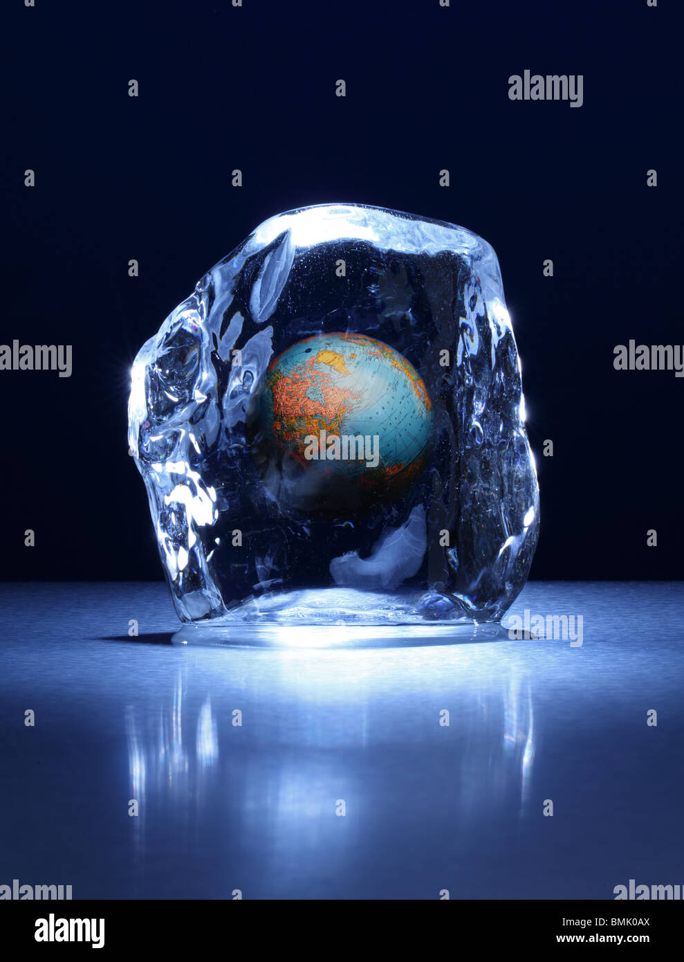 Un blocco congelato di ghiaccio con un globo mondo congelate all'interno su una superficie di metallo Foto Stock