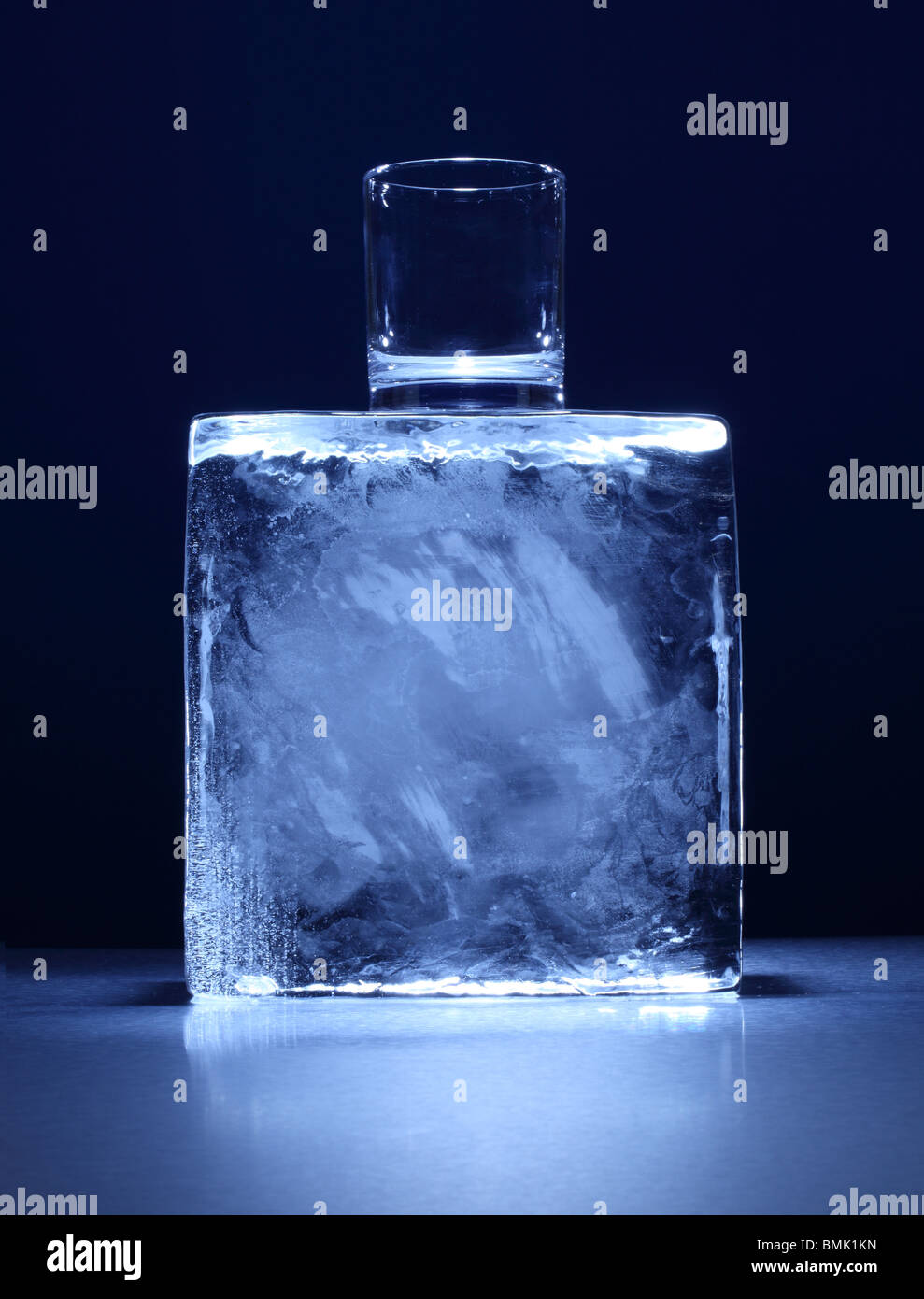 Un piccolo bicchiere sulla parte superiore di un blocco congelato di ghiaccio su una superficie di metallo Foto Stock