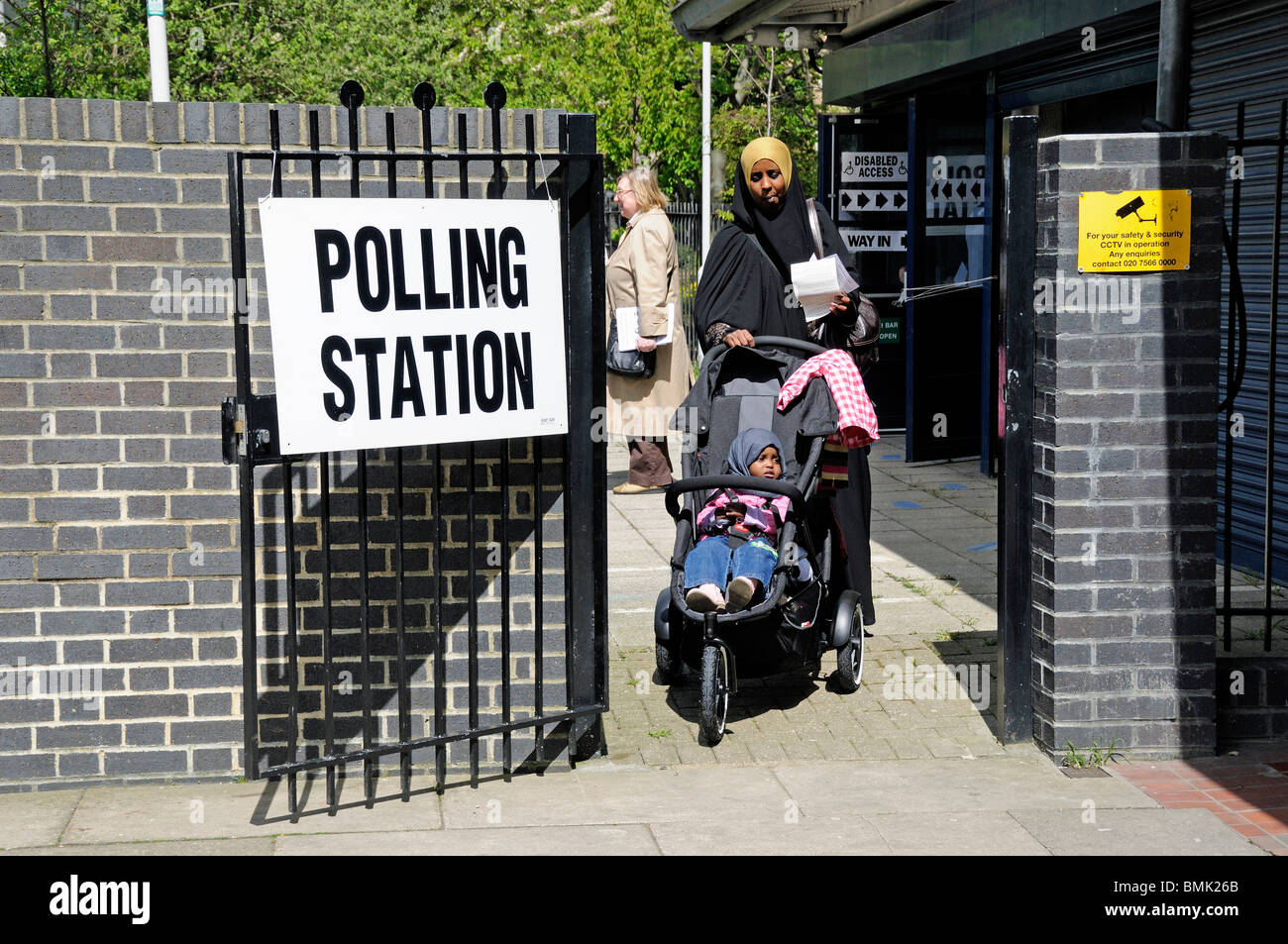 Madonna con bambino in sedia a rotelle lasciando la stazione di polling London Borough di Islington England Regno Unito Foto Stock