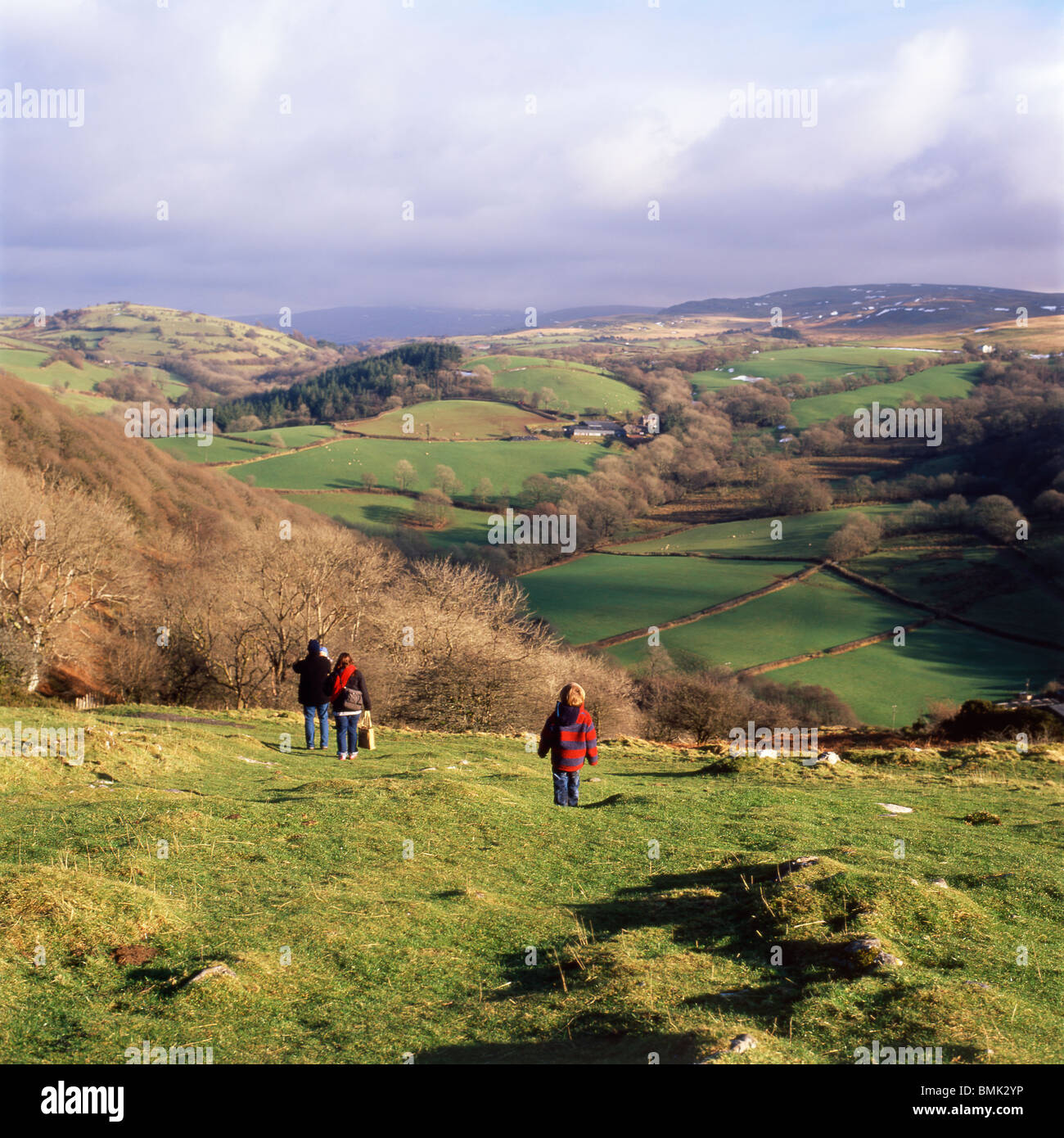 Una giovane famiglia a piedi giù per la collina in inverno da una visita a Carreg Cennan Castello, Trapp, Wales, Regno Unito KATHY DEWITT Foto Stock