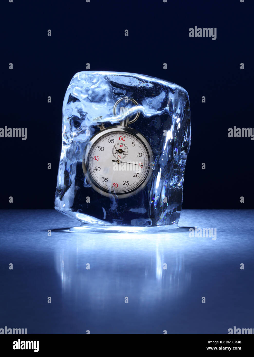 Un blocco congelato di ghiaccio con un cronometro congelate all'interno su una superficie di metallo Foto Stock