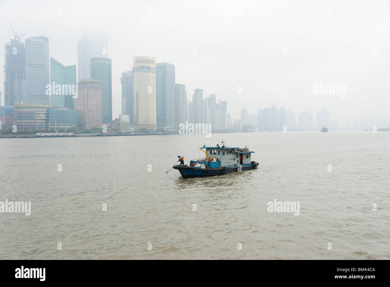 Piccola barca raccogliendo rifiuti sul fiume Huangpu, Shanghai, Cina Foto Stock