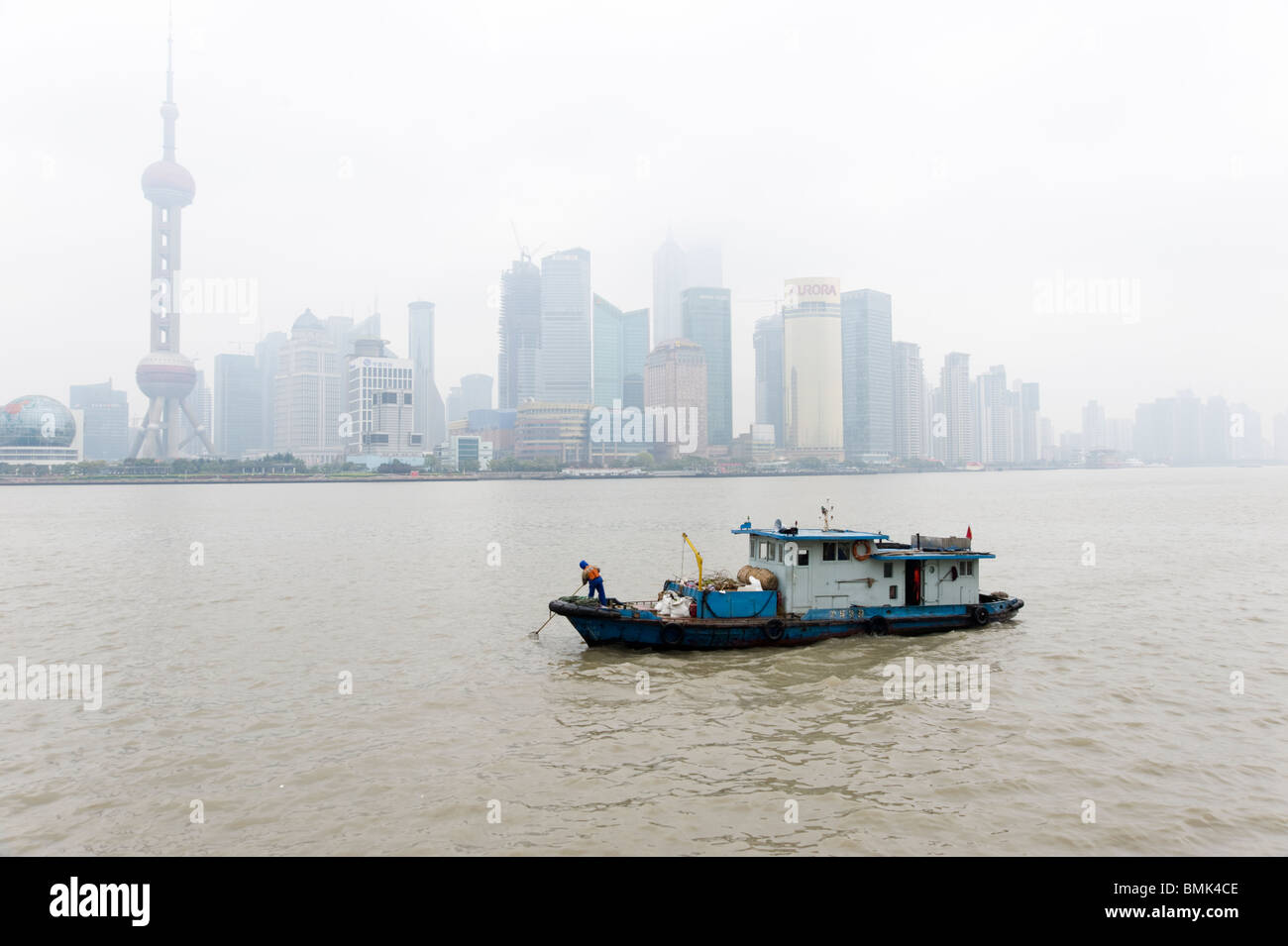Piccola barca raccogliendo rifiuti sul fiume Huangpu, Shanghai, Cina Foto Stock