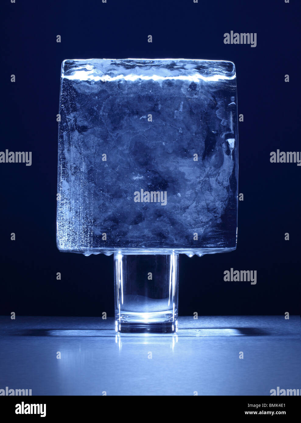Un blocco congelato di ghiaccio sulla sommità di un piccolo bicchiere Foto Stock