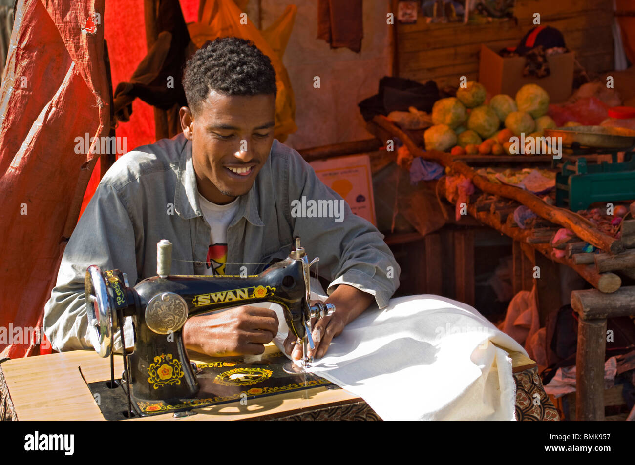 Giovane maschio taylor lavora con vecchio nero pedale-powered macchina da cucire nella sua plastica arancione-walled shop in Addis Abeba, Foto Stock