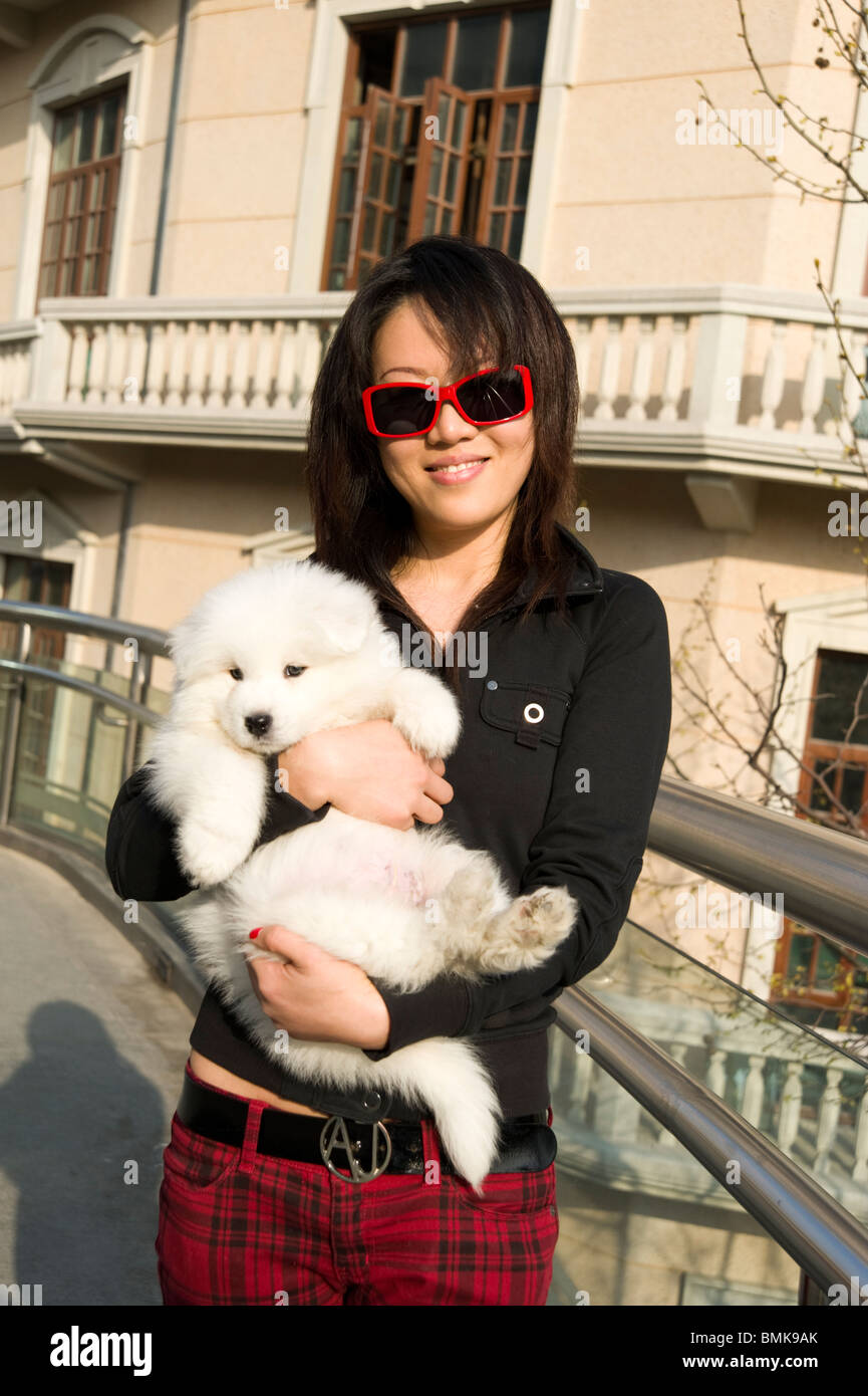 Moda giovane donna mentre tiene il suo pedigree pet cane, Shanghai, Cina Foto Stock