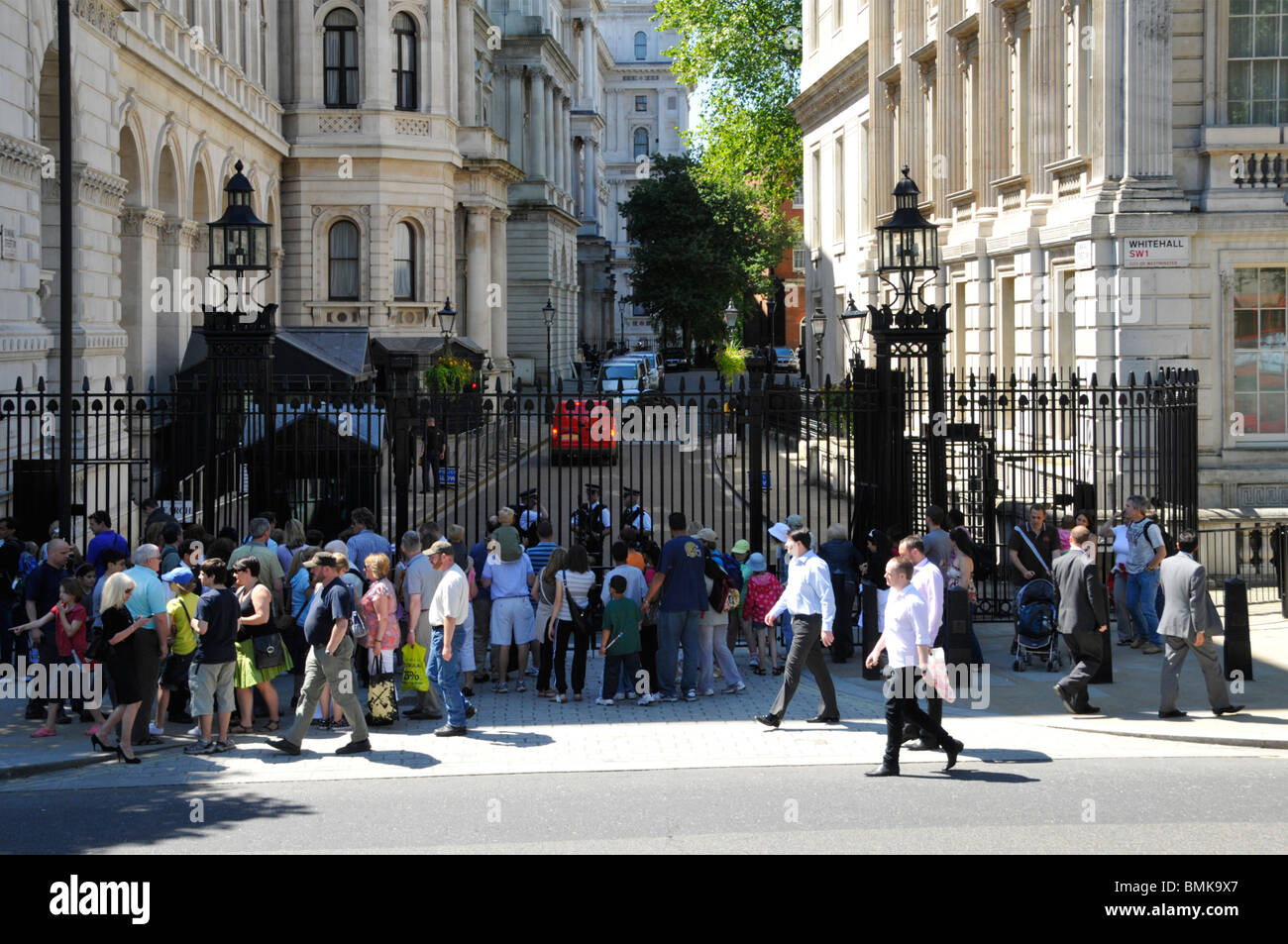 Turisti sul lato di Whitehall di Downing Street di fronte in acciaio cancelli di sicurezza comandati da Metropolitan poliziotti Londra Inghilterra REGNO UNITO Foto Stock