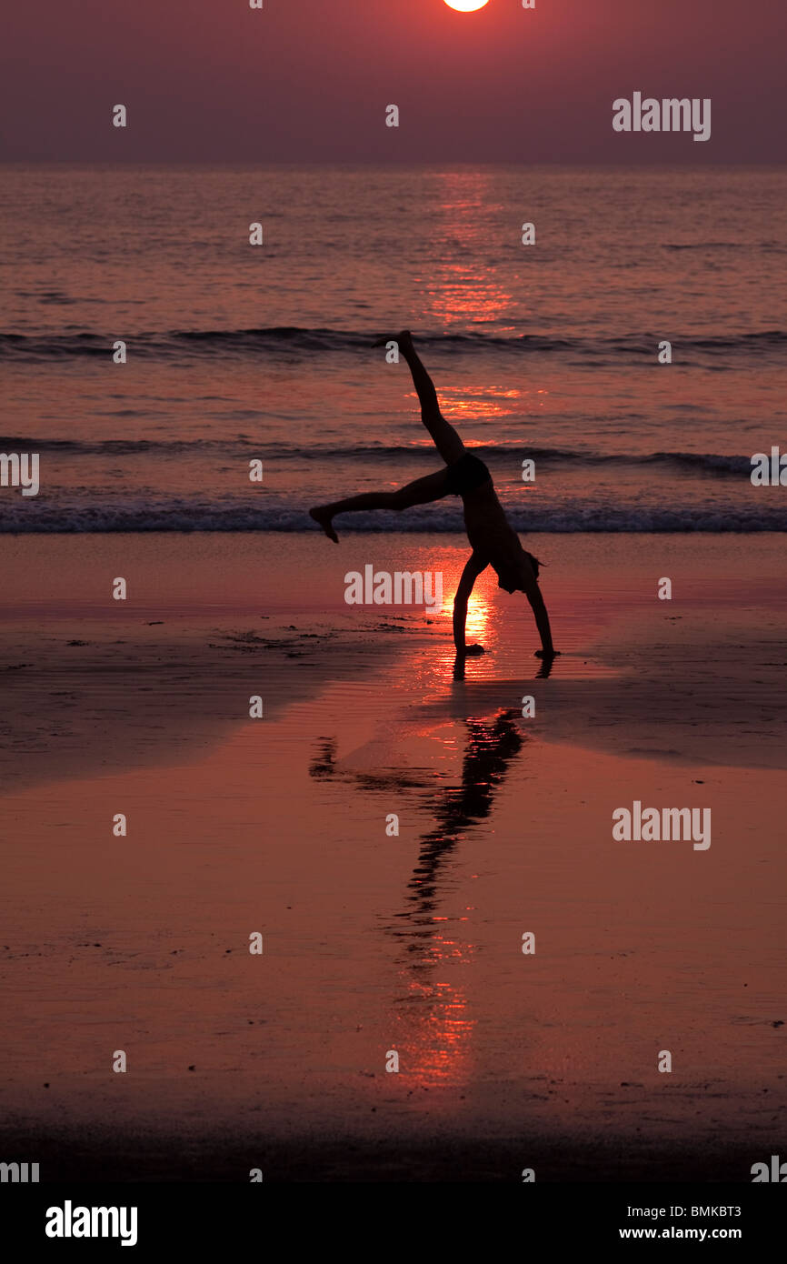 L'uomo facendo un handstand mentre facendo yoga a Kudle beach, Gokarna, India Foto Stock