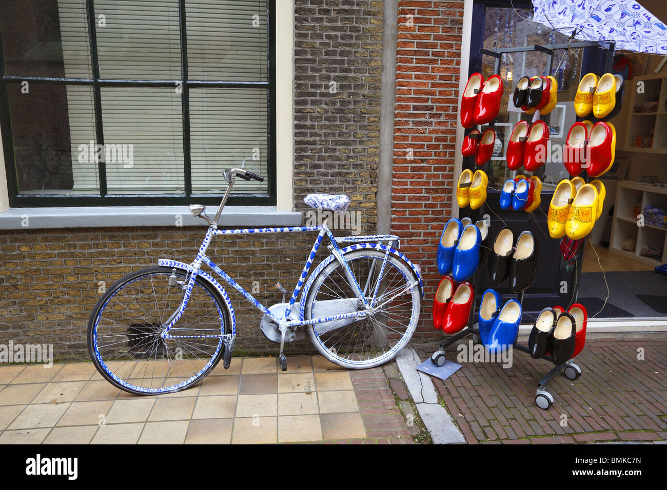 Zoccoli di legno in vendita a Delft, Olanda, a fianco di una bicicletta decorate in Delft Pottery blu e bianco Foto Stock