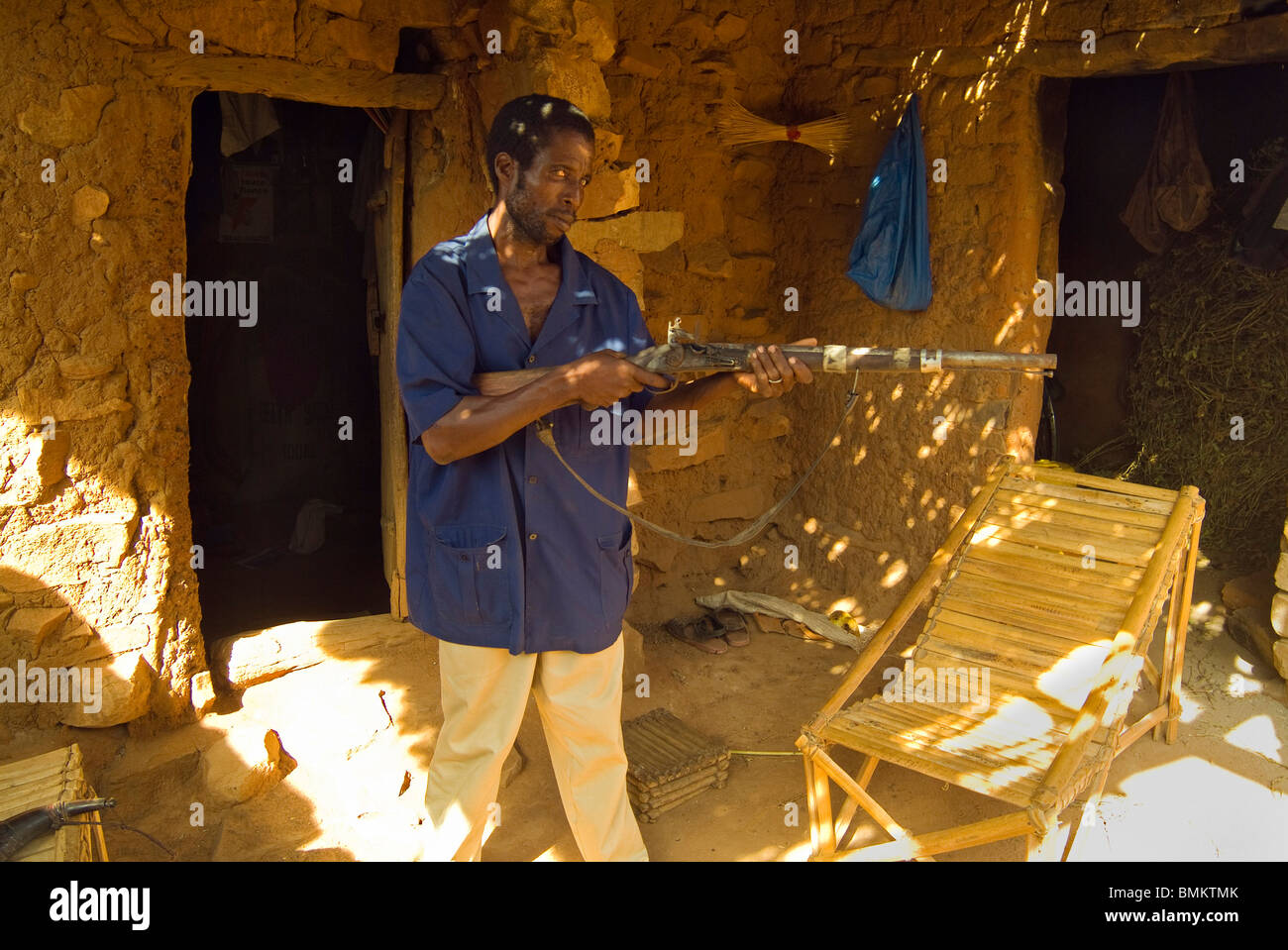 Africa Africa Occidentale, Mali, Songo Village. Songo uomini armati con un fucile sulla parte anteriore portico di casa sua. Foto Stock