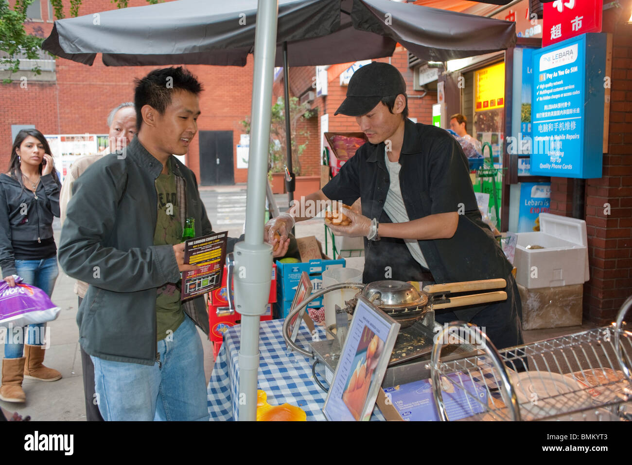 Londra, Regno Unito, Chinatown, Chinese Man Buying Take Way Street Food at Street Vendor Outside Store, migrante europa, negozio multietnico Street, giovane uomo Foto Stock