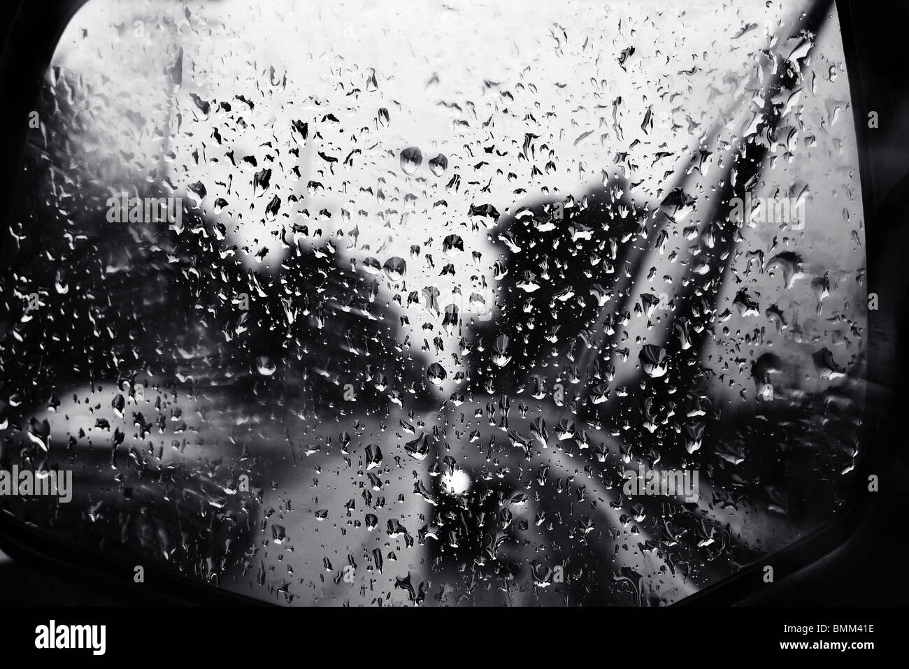 Le gocce di pioggia della specchio auto su una solitaria grigia giornata piovosa. Foto Stock
