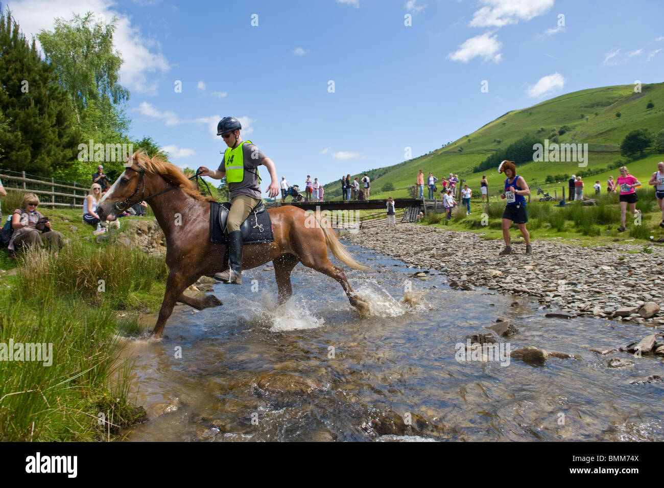 Guide cavalli e attraversare il fiume ford a Abergwesyn nell'uomo v corsa di cavalli a Llanwrtyd Wells Powys Mid Wales UK Foto Stock