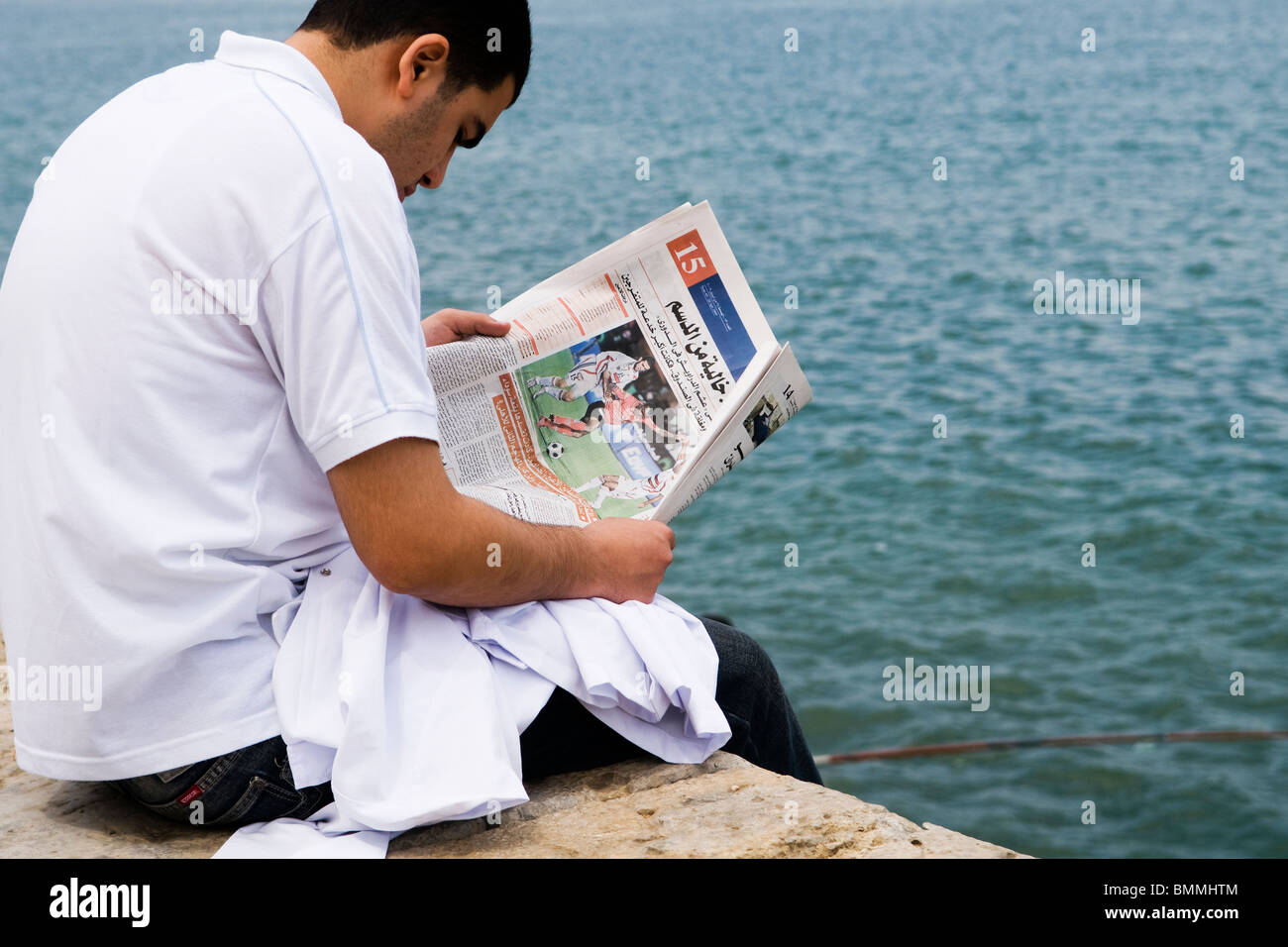 Un uomo egiziano la lettura di notizie di sport in Alessandria, Egitto. Foto Stock