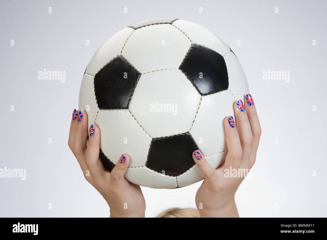 Mano con bandiera britannica dipinta su unghie tenendo un calcio Foto Stock