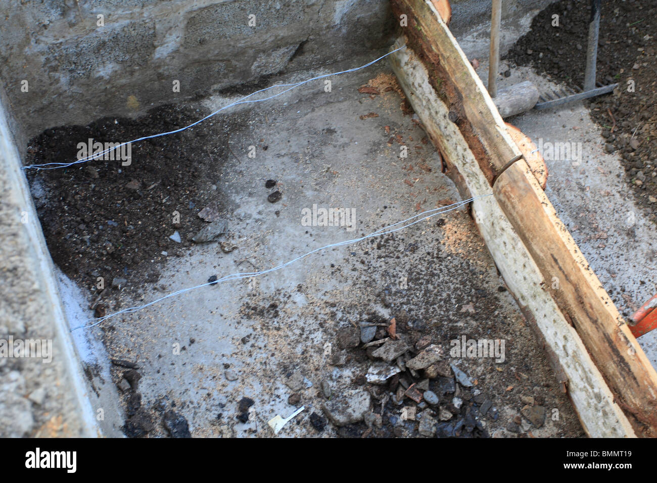 Costruzione di un letto rialzato- usando il filo per mantenere il letto in legno i lati al posto sul basamento in cemento Foto Stock