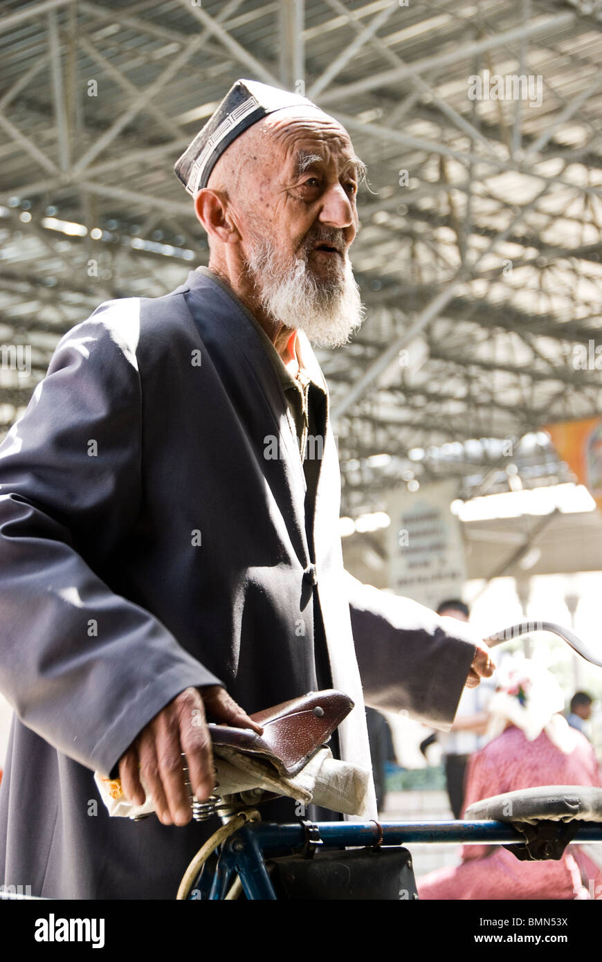 Il vecchio uomo in un marketwith la sua bicicletta, Uzbekistan, in Asia. Foto Stock