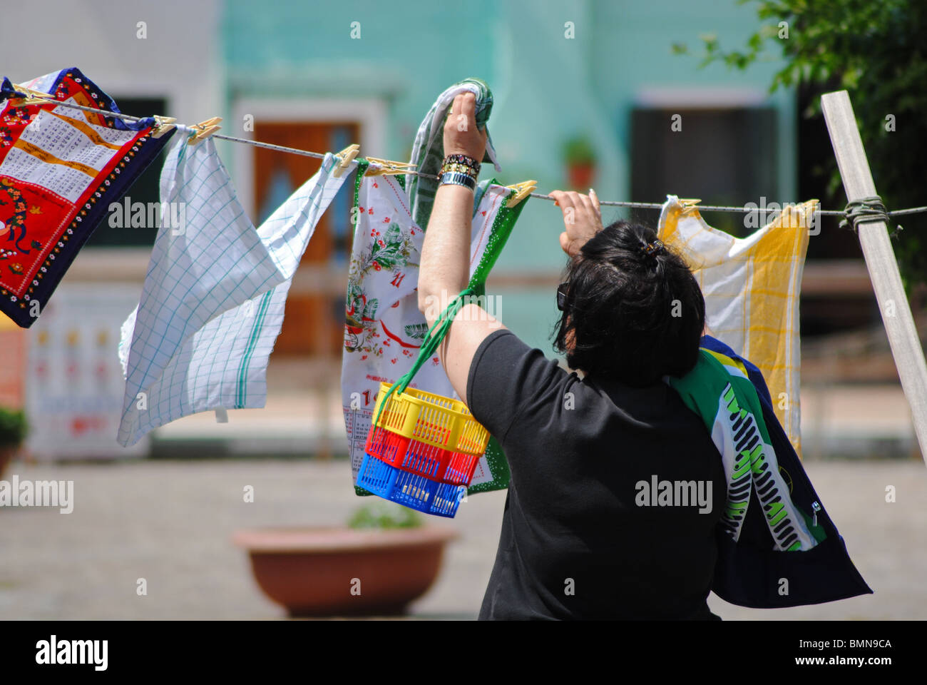 Donna italiana appendere i vestiti su una linea di lavaggio, Burano, Italia Foto Stock