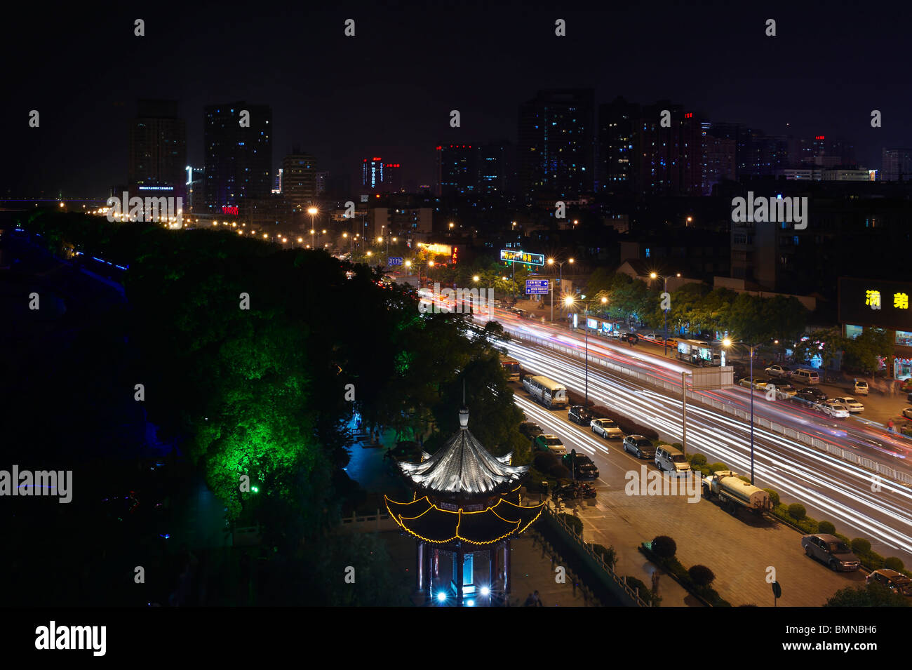 Sentieri di luce dai fari degli autoveicoli acquisiti su una strada principale molto trafficata in Changsha city, nella provincia del Hunan, Cina, contro la silhouette della città. Foto Stock