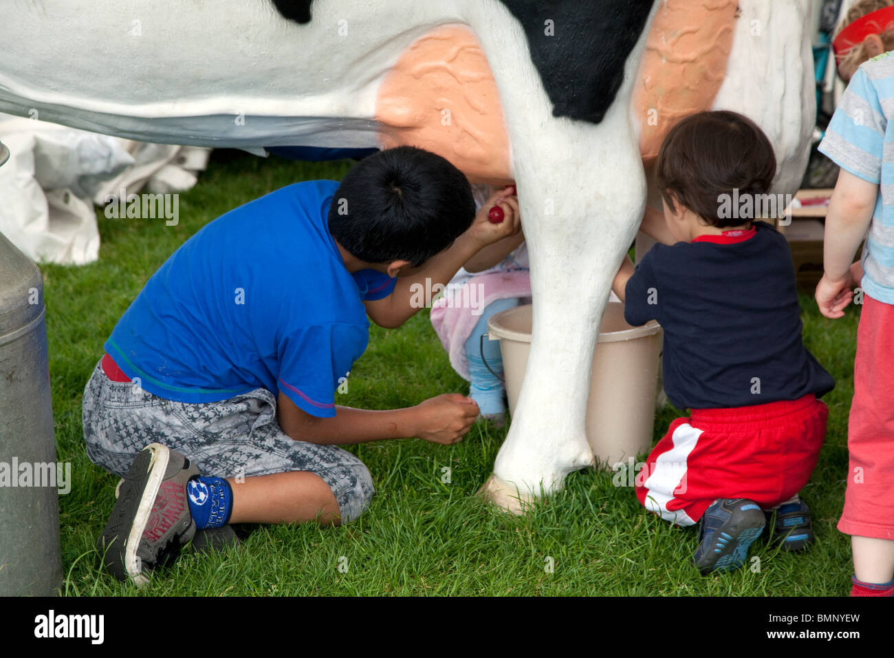 I bambini di mungere una mucca modello a Camden Fiera Verde, Londra Foto Stock