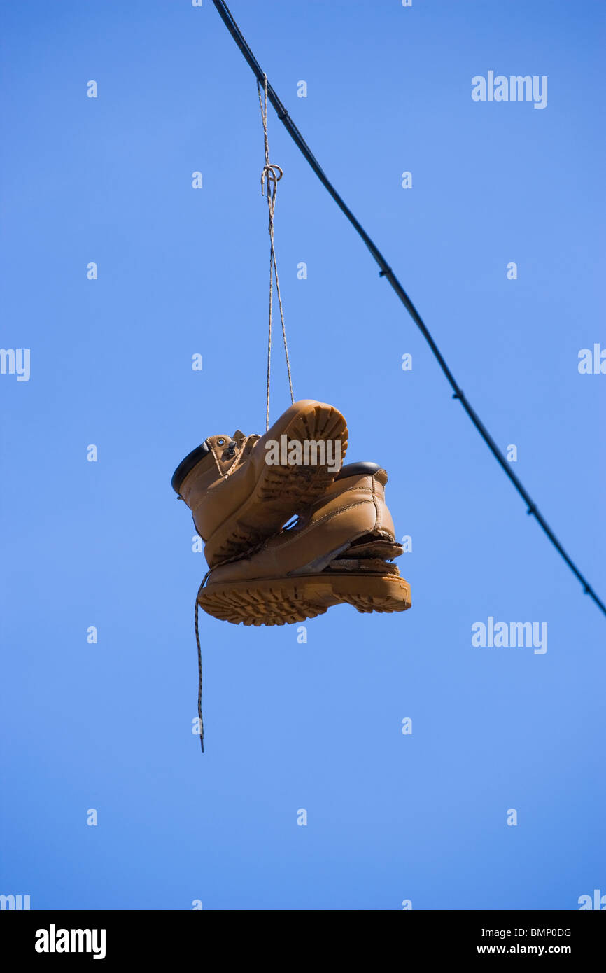 Coppia di scarponi appesa sopra il cavo elettrico con sfondo cielo,l'abuso di droga,l'assunzione di droga,spaccio di droga,addict,tossicodipendenti, Foto Stock
