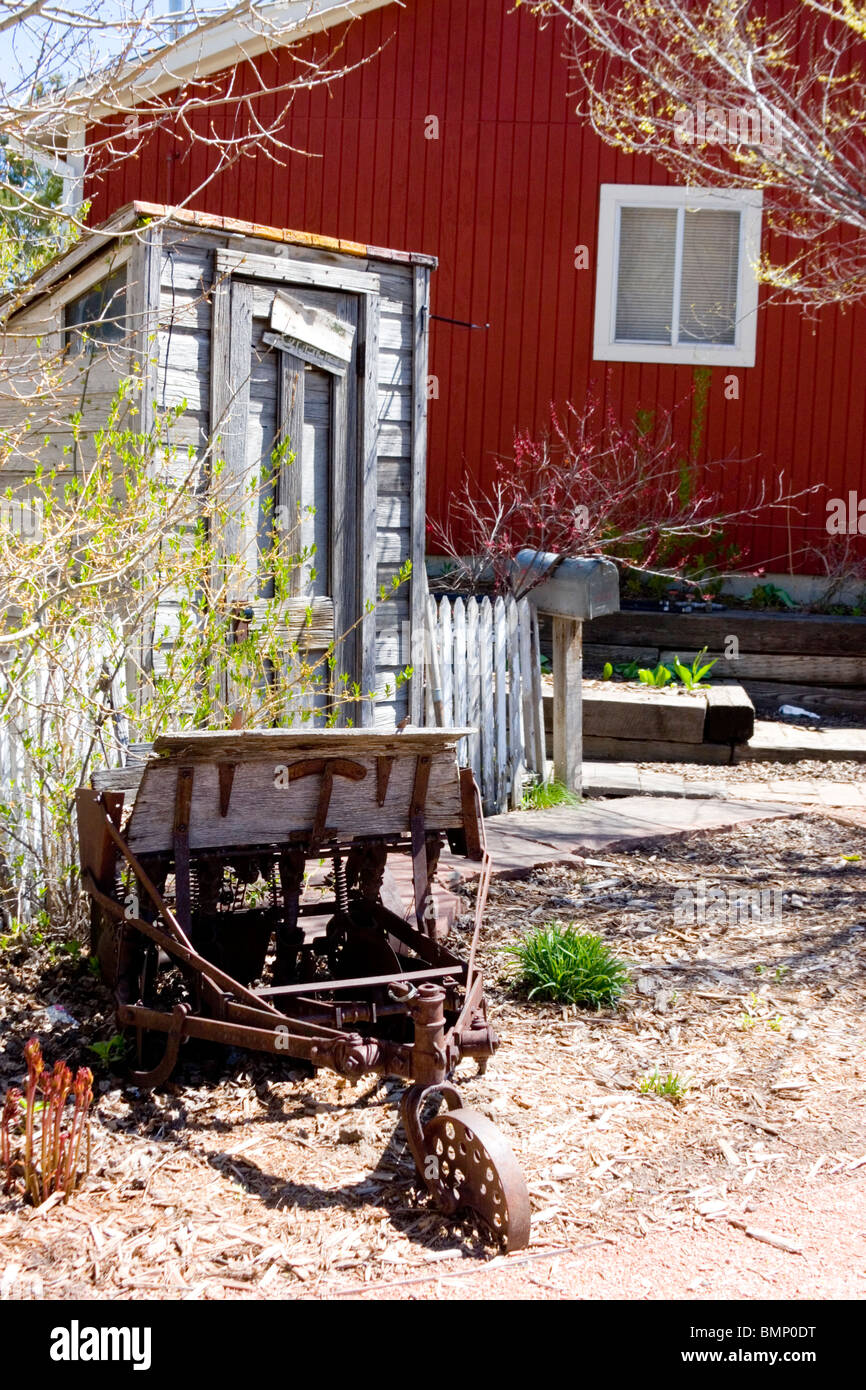 Vintage dipendenza e antico aratro nei pressi di un caratteristico granaio rosso. Foto Stock