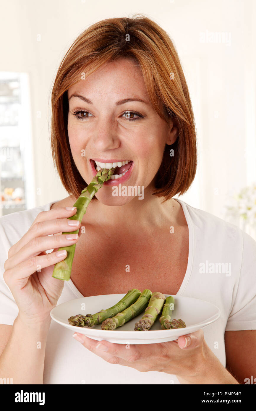 Donna mangiare asparagi Foto Stock