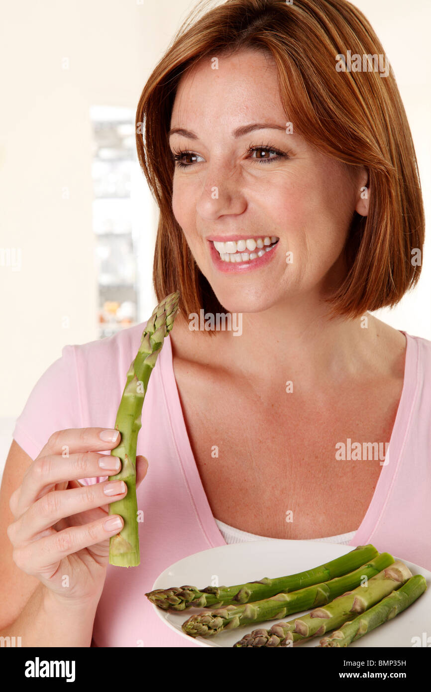 Donna mangiare asparagi Foto Stock