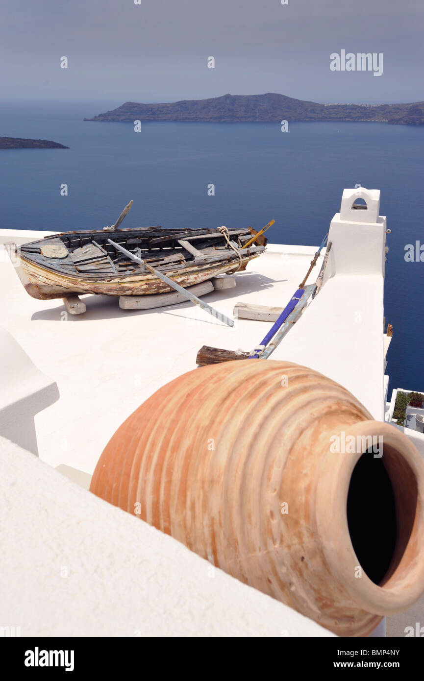 Urna di terracotta e la vecchia barca a remi sul tetto di un hotel a Firostefani Santorini, Cicladi Grecia Foto Stock