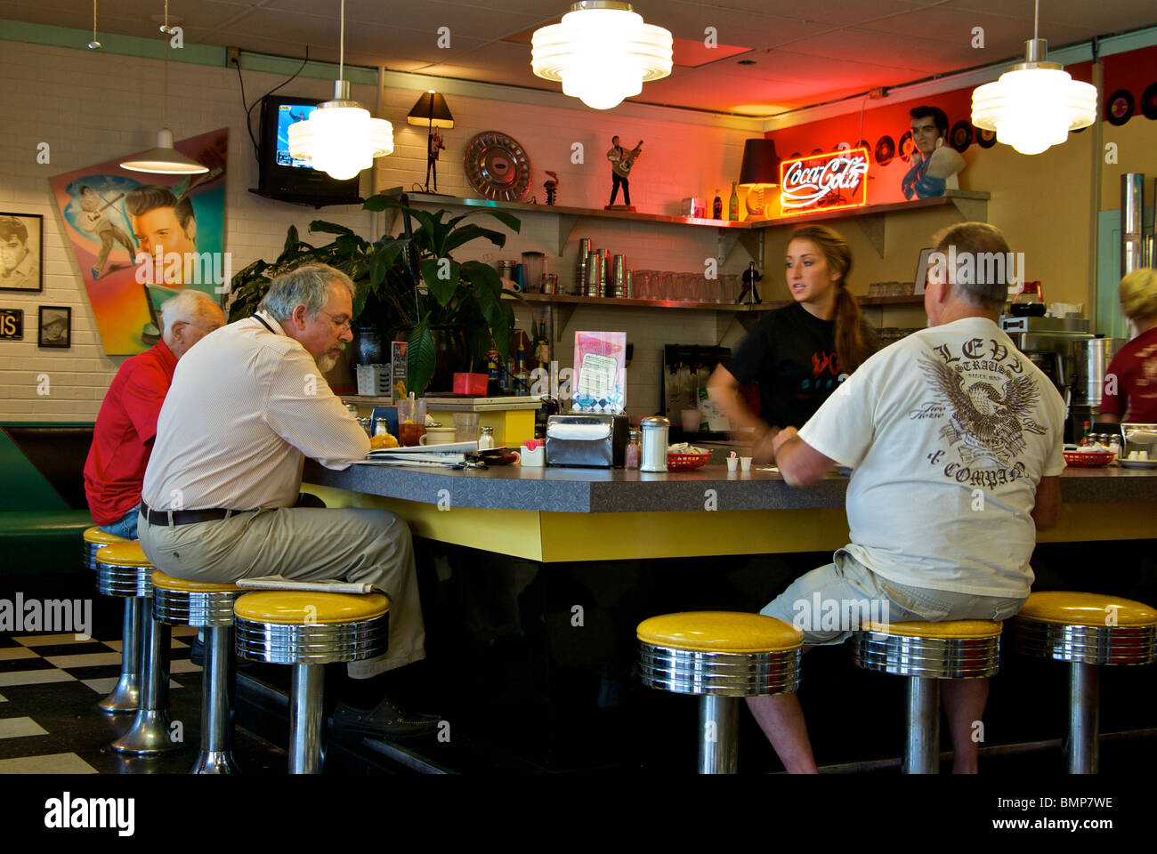 Patroni seduto su chrome sgabelli rifilate presso il cafe bar cameriera in slow shutter motion blur Hub City Diner Lafayette Louisiana USA Foto Stock