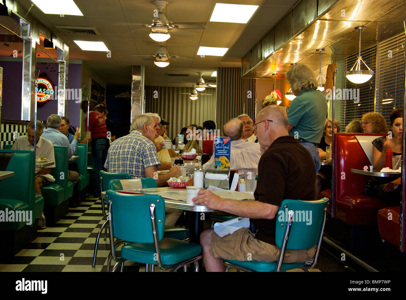 Proprietario Jimmy Guidry Hub City Diner parlando con regolari patroni cameriere in slow shutter sfocatura del movimento Foto Stock
