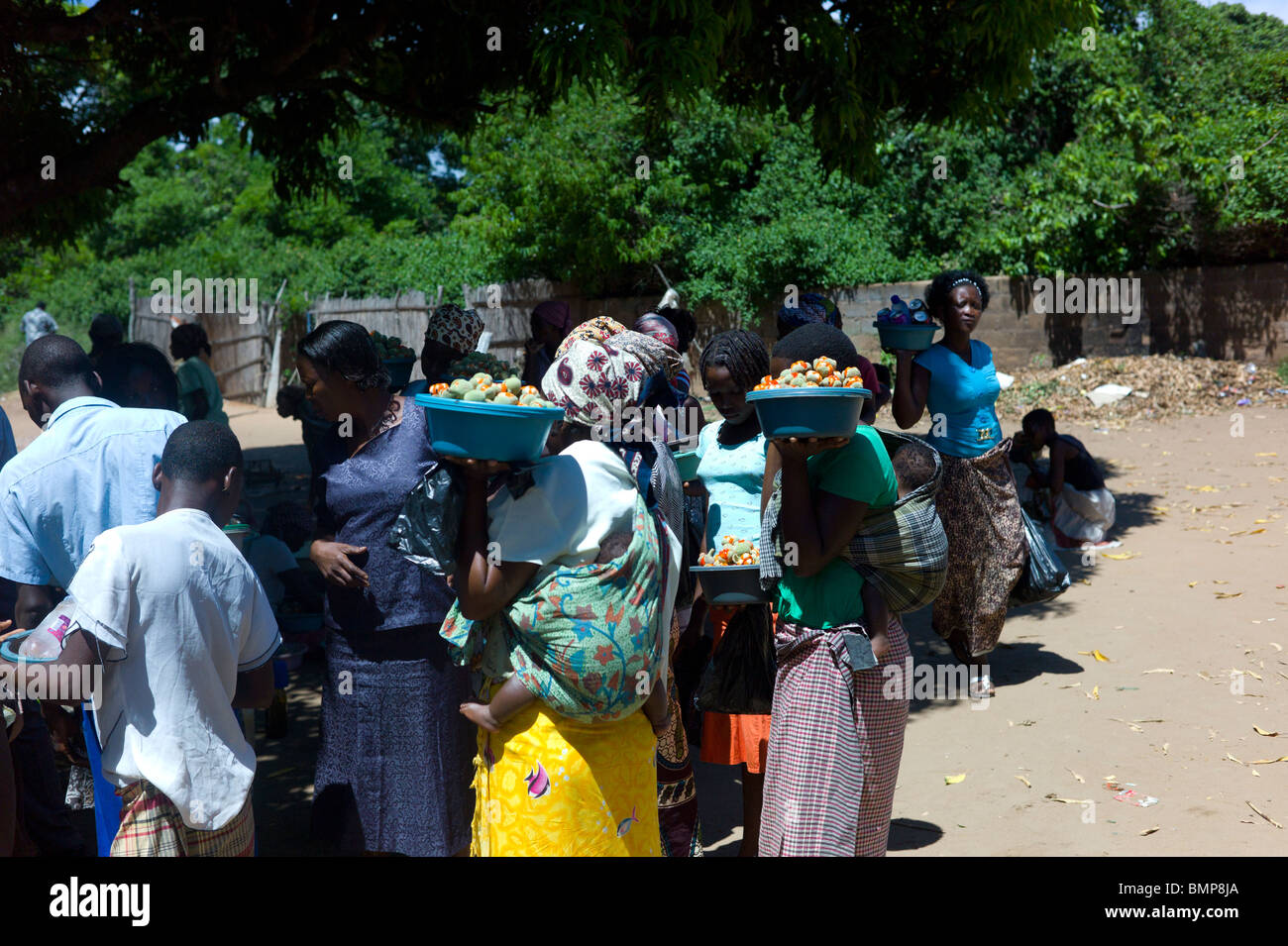 Donne locali vendono frutta ai viaggiatori in corrispondenza di un bordo strada fermata bus in un piccolo villaggio in Mozambico, Africa. Foto Stock