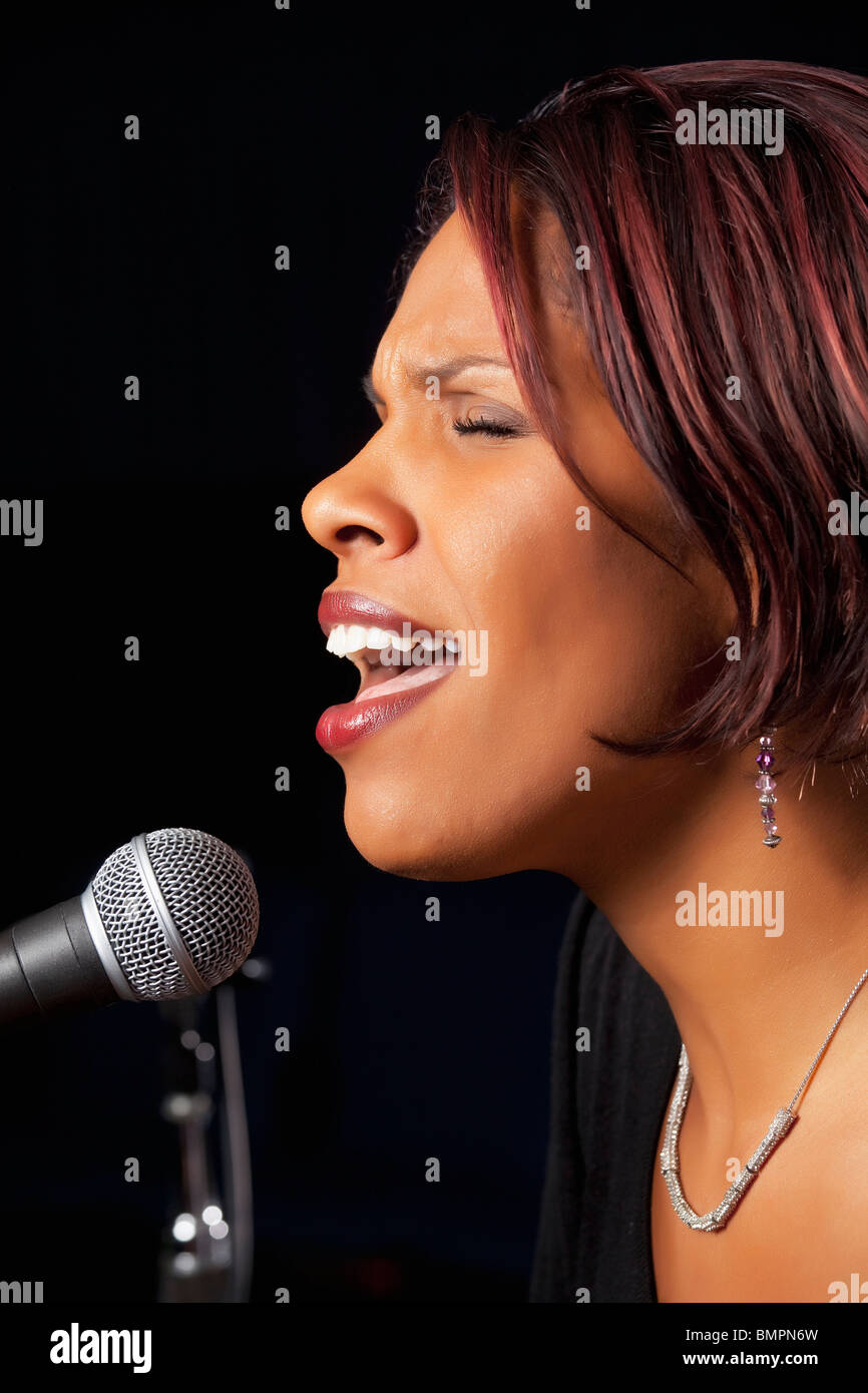 Donna cantare nel microfono Foto Stock