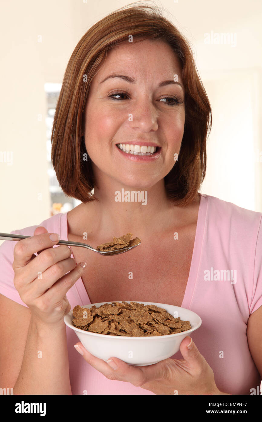 Donna mangiare scaglie di crusca di cereali per la prima colazione Foto Stock