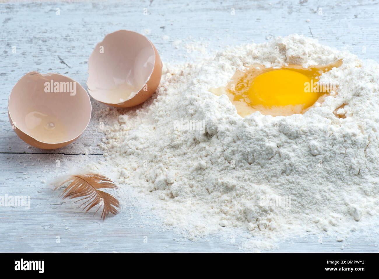 Un uovo rotto in alcuni Farina, con il guscio e una gallina giù al lato Foto Stock