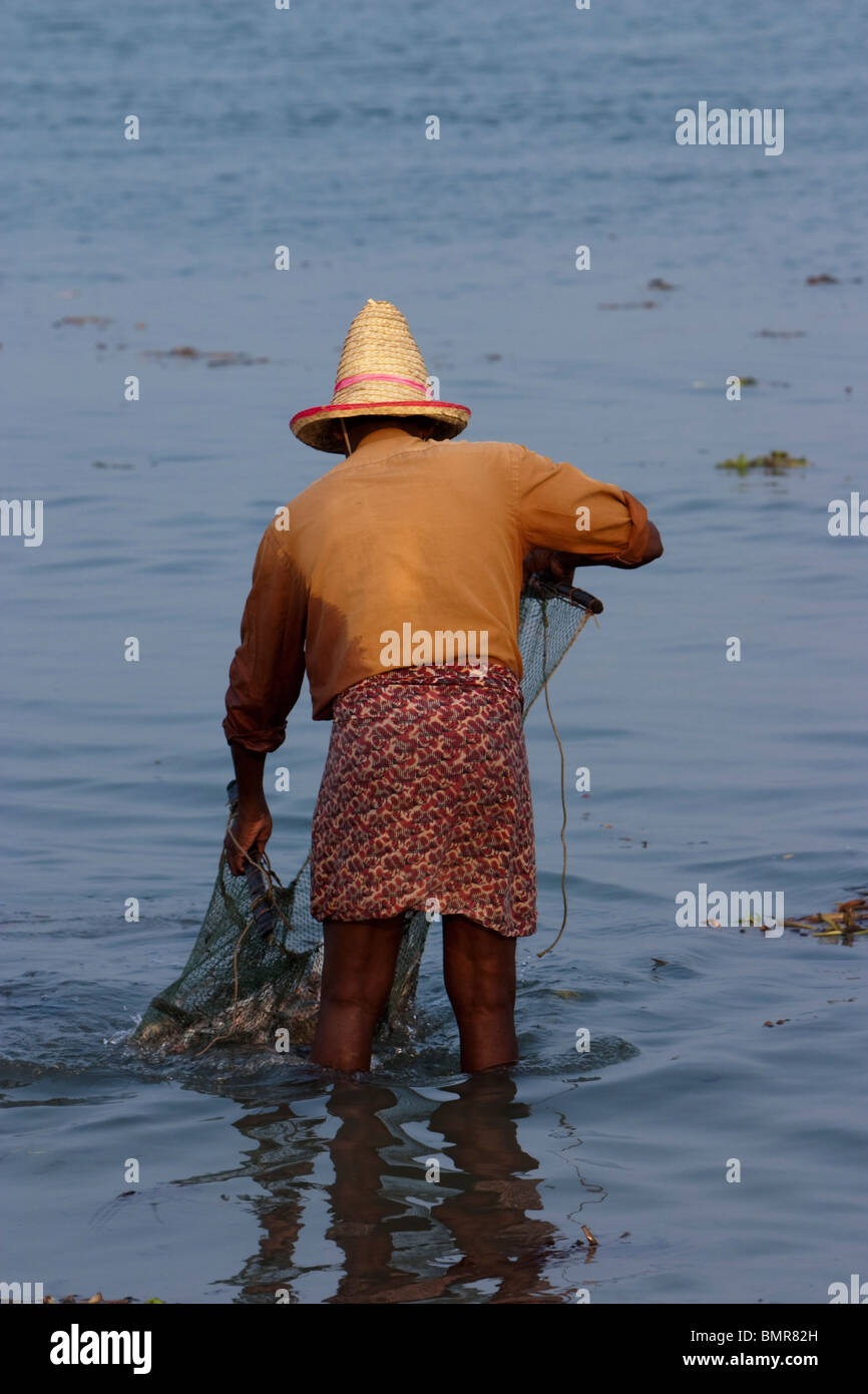 Un pescatore per la cattura di pesce utilizzando una rete ponderata in Kerala, India. Foto Stock